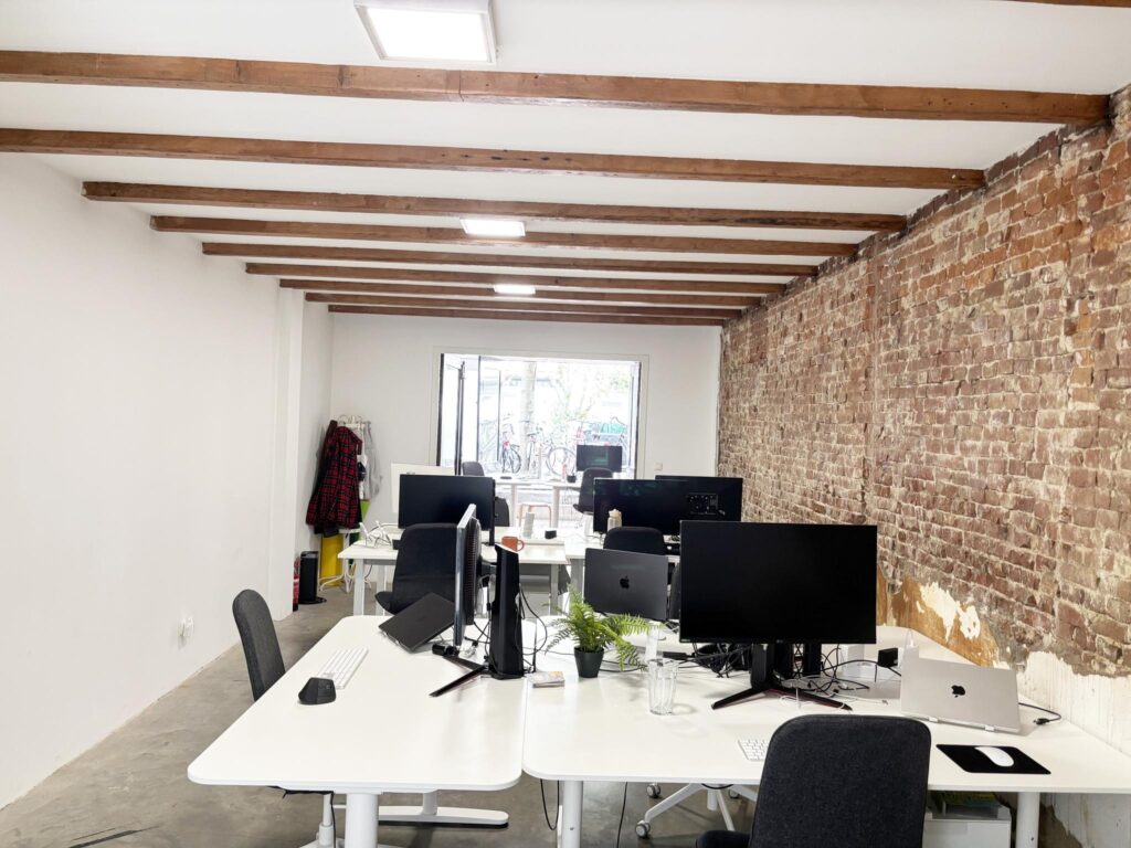 Modern open office space on Van Ostadestraat with exposed brick wall, white desks, and computer workstations.